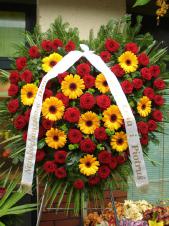 Wieniec pogrzebowy z żywych kwiatów, kształt serca, wielkość: bardzo duży, róża pąsowa, gerbera pomarańczowa, liść palmy podkład jodłowy, zieleń dekoracyjna, szarfa satynowa 7cm, druk komputerowy (+20 zł).