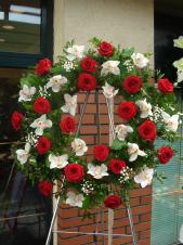 Wieniec pogrzebowy z żywych kwiatów, kształt okrągły średnica ok. 80cm (wieniec rzymski), róże pąsowe, storczyki białe (Cymbidium), zieleń dekoracyjna.