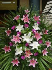 Wieniec jednopłaszczyznowy, lilia różowa i biała, storczyk fioletowy (Phalaenopsis), zieleń dekoracyjna, liść palmy, podkład jodłowy.