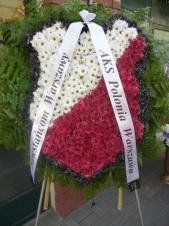 Wieniec pogrzebowy z kwiatów żywych, herb klubu sportowego, chryzantemy gałązkowe białe, czerwone i czarne, podkład jodłowy, liście paproci, szarfa satynowa 7cm. szer.