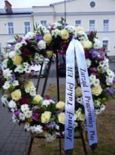 Wieniec pogrzebowy z żywych kwiatów, kształt okrągły średnica ok. 100cm,  róże kremowe, chryzantemy białe, storczyki ciemnoróżowe, eustomy fioletowe, goździki gałązkowe ciemnoróżowe, chryzantemy zielone, tulipany fioletowe, szarfa satynowa 7cm. szer.