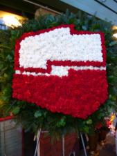 Wieniec nietypowy w kształcie logo, wielkość: ok. 1,2 m, goździki białe i czerwone, chryzantemy białe, zieleń dekoracyjna.