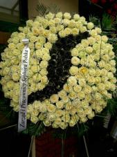 Wieniec pogrzebowy okrągły, średnica: ok. 100 cm., kremowe róże z malowanym logo w kolorze czarnym, podkład jodłowy, zieleń dekoracyjna.