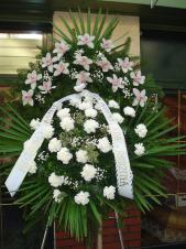 Wieniec z żywych kwiatów, wielkość: średni, storczyki białe (Cymbidium), goździki białe, liść palmy, podkład jodłowy, szarfa taśma plastikowa, pismo ręczne.
