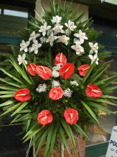 Wieniec z żywych kwiatów, wielkość: średni, storczyki białe (Cymbidium), anthurium czerwone, liść palmy, podkład jodłowy, zieleń dekoracyjna.