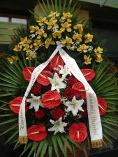Wieniec z żywych kwiatów, wielkość: bardzo duży, lilie białe (Syberia), storczyki złote (Cymbidium), anthurium czerwone, róże pąsowe, liść palmy, podkład jodłowy, zieleń dekoracyjna, szarfa satynowa 10cm, druk komputerowy.