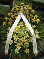 Wieniec z żywych kwiatów, wielkość: bardzo duży, lilie kremowe (Conca D'Or), storczyki złote (Cymbidium), anthurium zielone (Midori), liść palmy, podkład jodłowy, zieleń dekoracyjna, szarfa satynowa 10cm, druk komputerowy.