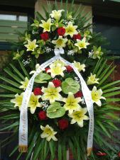 Wieniec z żywych kwiatów, wielkość: duży, lilie kremowe (Conca D'Or), róże pąsowe, storczyki zielone, anthurium zielone (Midori), liść palmy, podkład jodłowy, zieleń dekoracyjna, szarfa satynowa 7cm, druk komputerowy.