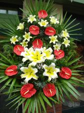 Wieniec z żywych kwiatów, wielkość: duży, lilie kremowe (Conca D'Or), anthurium czerwone, liść palmy, podkład jodłowy, zieleń dekoracyjna.