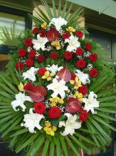 Wieniec z żywych kwiatów, wielkość: duży, róże pąsowe, storczyki złote (Cymbidium), lilie białe (Casablanca), anthurium bordowe (Safari), liść palmy, podkłąd jodłowy, zieleń dekoracyjna.