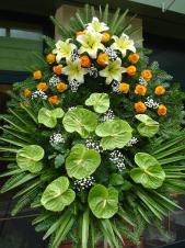 Wieniec z żywych kwiatów, wielkość: średni, lilie kremowe (Conca D'Or), róże herbaciane, anthurium zielone (Midori), liść palmy, podkład jodłowy, zieleń dekoracyjna.