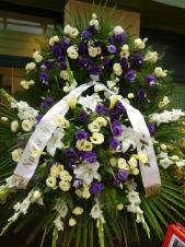 Wieniec z żywych kwiatów, wielkość: duży (ok. 1,6 m), mieczyk biały, eustoma fioletowa, eustoma kremowa, lilia biała, cantadeskia żółta, , liść palmy, podkład jodłowy, zieleń dekoracyjna.