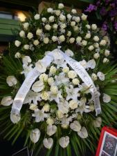 Wieniec z żywych kwiatów, wielkość: bardzo duży, anthurium białe, róża kremowa (White Naomi), lilia biała, liść palmy, zieleń dekoracyjna, podkład jodłowy, szarfa satynowa o szer. 10 cm (+30 zł).
