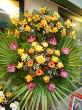 Wieniec z żywych kwiatów, wielkość: duży, storczyki złote (Cymbidium), róże herbaciane, anthurium bordowe, gerbery złote, liść palmy, podkład jodłowy, zieleń dekoracyjna.