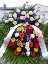Wieniec z żywych kwiatów, wielkość: średni, róże białe, irysy fioletowe,  storczyki żółte (Cymbidium), chryzantemy zielone i kremowe, gerbery złote, goździki gałązkowe, liść palmy, podkład jodłowy, szarfa plastikowa, druk komputerowy.