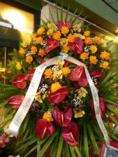 Wieniec z żywych kwiatów, wielkość: bardzo duży, storczyki złote (Cymbidium), róże herbaciane, anthurium bordowe, liść palmy, podkład jodłowy, zieleń dekoracyjna, szarfa plastikowa, nadruk złoty.