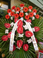 Wieniec z żywych kwiatów, wielkość: duży, gerbery czerwone,  storczyki białe (Cymbidium), anthurium czerwone, liść palmy, podkład jodłowy, szarfa satynowa, druk komputerowy (+20zł).