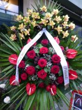 Wieniec pogrzebowy z żywych kwiatów, wielkość: duży, storczyki żółte, róże pąsowe, anthurium czerwone, liść palmy, podkład jodłowy, zieleń dekoracyjna, szarfa satynowa biała 7 cm. (+20zł)