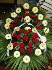 Wieniec  żywych kwiatów, gerbera kremowa, róża pąsowa, podkład jodłowy, zieleń dekoracyjna, liść plamy.
