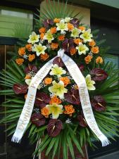 Wieniec pogrzebowy z żywych kwiatów, wielkość: bardzo duży, anthurium brązowe (Choco), róże herbaciana (Finnes), lilie kremowe (Conca D'or), liście palmy, podkład jodłowy, zieleń dekoracyjna, szarfa satynowa 10cm, druk komputerowy.